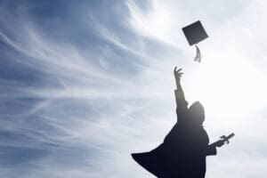 A student tossing up hats over blue sky