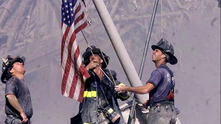 Three firefighters rasing a flag at teh World Trade Center in New York.